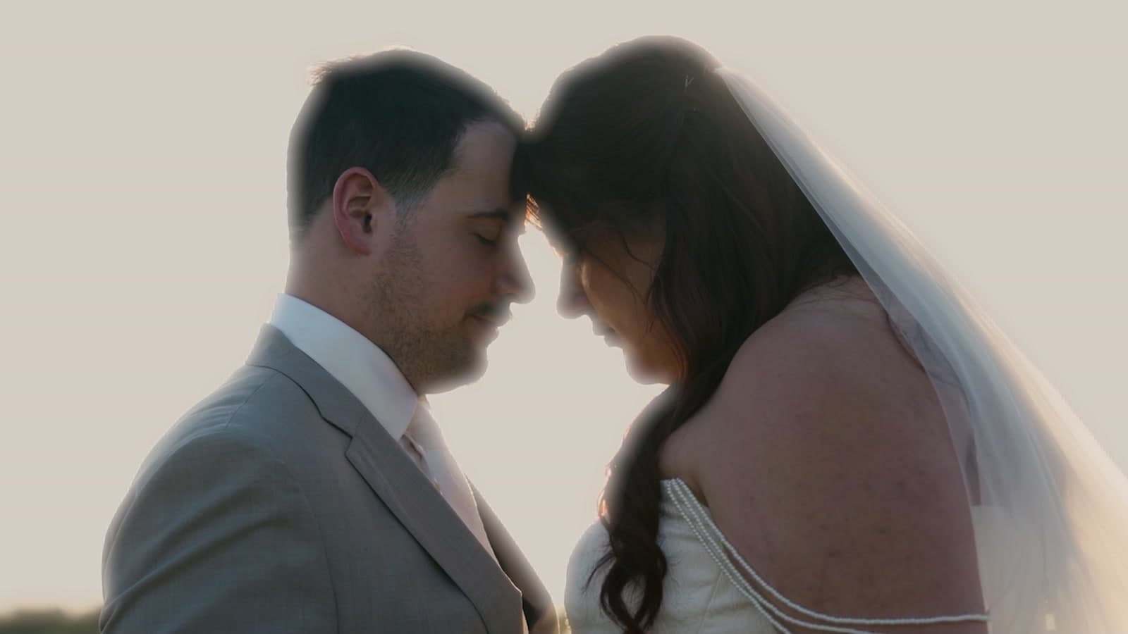 A bride and groom forehead to forehead in soft evening light